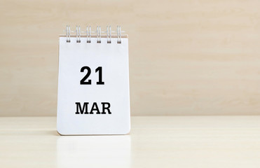 Closeup surface note book with black 21 mar word in page on blurred brown wood desk and wood wall textured background with copy space under window light