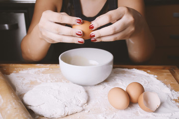 Woman breaking an egg into bowl.