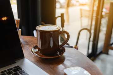 Coffee cup and laptop on wooden table in coffee shop. business concept