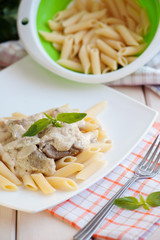 Penne pasta with meat and white sauce on a plate