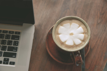 Coffee cup and laptop on wooden table in coffee shop. business concept