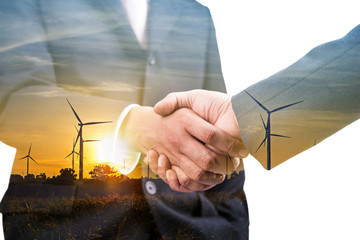 Double exposure of business hand shake with wind turbine 