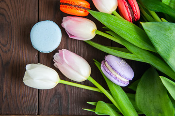 Rose-colored tulips with macarons on a wooden background