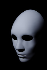 White mask with neutral expression and shadows on dark background