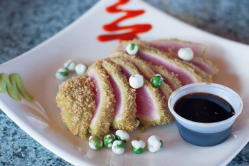 Seared fresh Ahi tuna slices with wasabi peas and sauce
