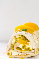 Meringue roulade with cream and passion fruit and peaches