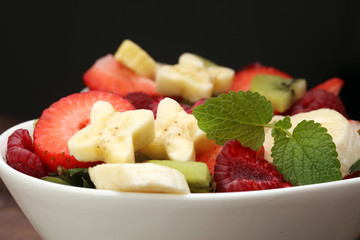 Bowl of healthy fresh fruit salad on wooden background