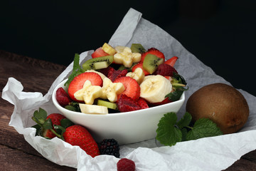 Bowl of healthy fresh fruit salad on wooden background