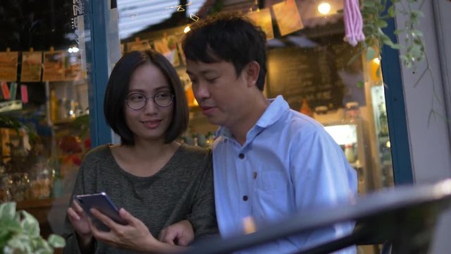 Asian couple using smartphone in cafe using Hand-held Panning