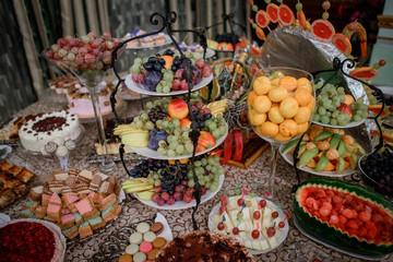 Tired steel dish with fruits stands on dinner table served with sweets