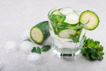 Cold and refreshing water with cucumber and mint on grey background. Summer drink cucumber...