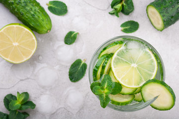 Refreshing water with cucumber, mint and lime on grey background top view. Summer drink cucumber...
