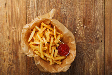 Serving Belgian fries served on paper in the basket, with one or two dips. On a wooden table.