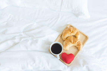 Fototapeta na wymiar Breakfast in bed with croissants and coffee with red heart in the tray