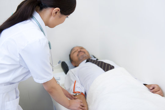 Female nurse preparing saline drip for mature man