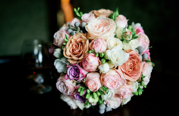 Gorgeous wedding bouquet made of tender pink and orange roses lies on table