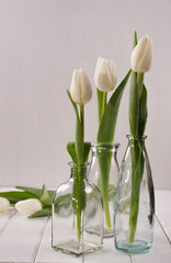 Three glass bottles with tulips in minimalistic.