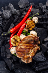 grilled meat with mushrooms, garlic and hot pepper in the background coal