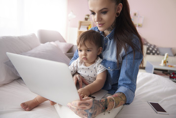 Mother working with little son at home interior