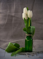White tulips in green glass bottle,vases. 