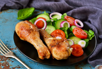 Baked chicken with a side dish of vegetable salad on the old, blue background