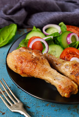 Baked chicken with a side dish of vegetable salad on the old, blue background