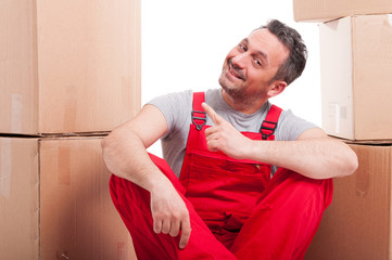 Mover man sitting down and pointing surrounded by boxes