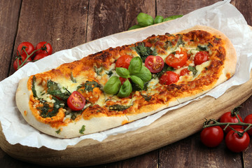 Hot pizza slice with melting cheese on a rustic wooden table.