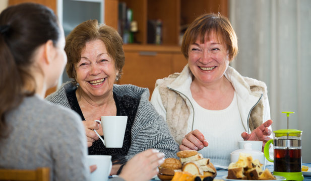Senior women talking with girl while tea drinking