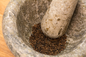 Grinding cardamom in a rustic mortar