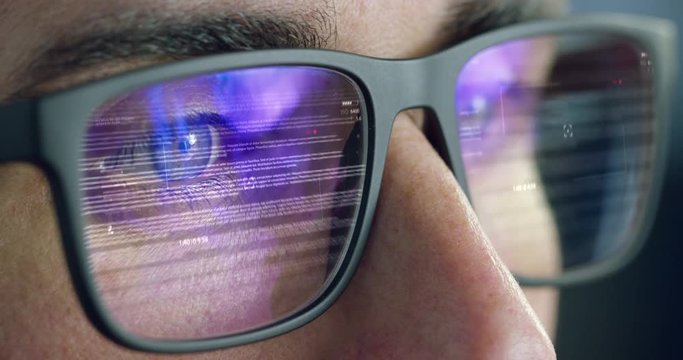 Close up of young businessman with blue eyes wearing the glasses looking on the waveform lines and data