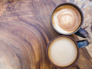 Two cups of hot coffee cappuccino on wood texture background, top view.