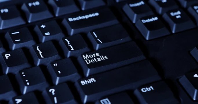Close up of a male finger presses a button with text of More Details on the computer keyboard