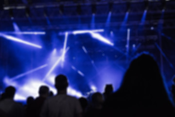 De-focused concert crowd / people silhouettes enjoying music.