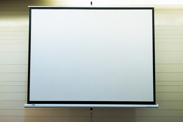 Front view of lecture room with empty white projector screen