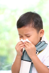 Little boy blowing his nose into tissue. healthcare and medical concept.