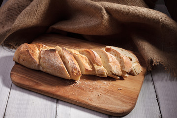 Sliced baguette on wood board.