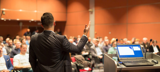 Speaker giving a talk on corporate business conference. Audience at the conference hall. Business...