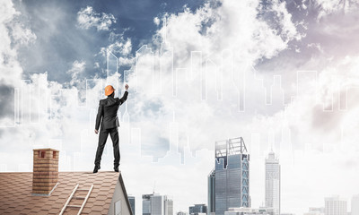 Man architect draw silhouette of modern city on blue sky. Mixed 