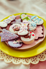 Colorful cupcakes covered with pink glaze stand on pink and yellow plate