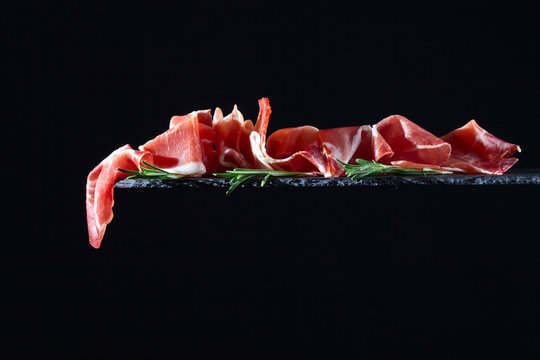 prosciutto with rosemary on a black  background