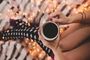 Fototapeta na wymiar Junge Frau liegt im Bett mit Tasse Tee
