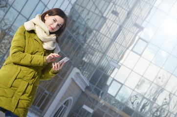 Young woman with mobile phone outdoor in sunny winter day.