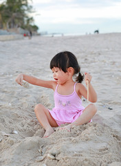 Fototapeta na wymiar Portrait Kid girl playing sand at the beach