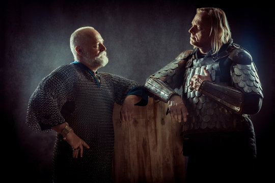 Two powerful knights resting in the tavern. Dark background.