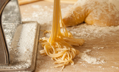 making fresh pasta spaghetti with pasta maker, dough and flour