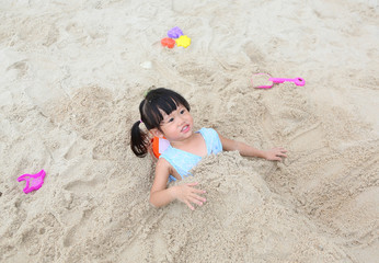 Fototapeta na wymiar Cute child girl playing sand at the beach