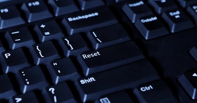 Human hand pressing a Reset button on the computer keyboard