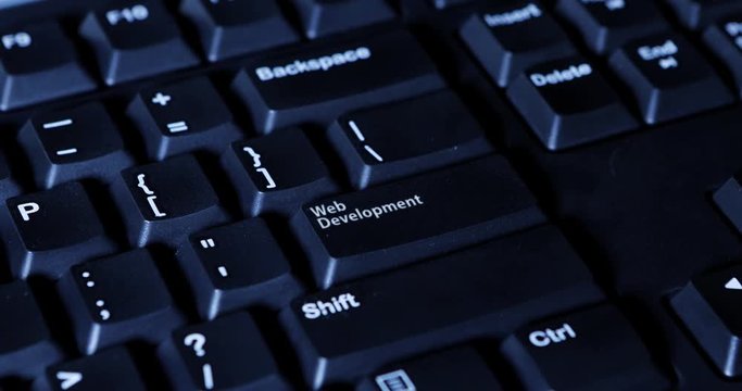 Close up of a male hand pushing a button of Web Development on the computer keyboard