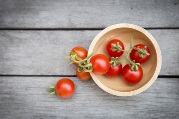 Fresh red cherry tomato in round wooden bowl over vintage background